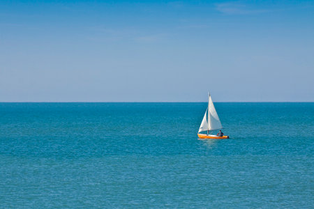 Lonely man in a small sailboat in the middle of a calm sea - Unrecognizable man.のeditorial素材
