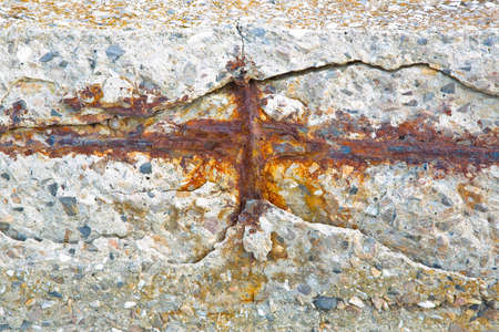 Old reinforced cracked concrete structure with damaged with rusty metallic reinforcement bars.