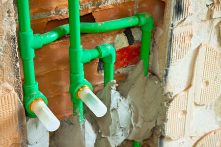 Detail of a new hydraulic system with a green polypropylene pipes for hot and cold water in an italian construction site.の写真素材