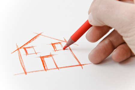 Hand drawing an house with a pencil on white sheetの写真素材