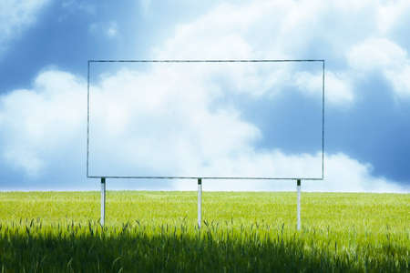 Blank advertising billboard immersed in a rural scene against a cloudy sky - image with copy spaceの写真素材