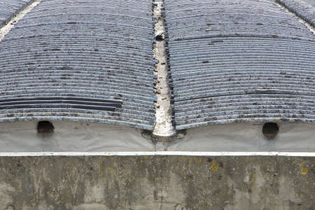 Old aged dangerous roof made of corrugated asbestos panels - one of the most dangerous materials in buildings and construction industry so-called hidden killer.の写真素材