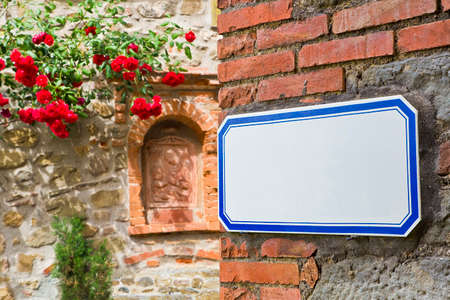 Blank road sign indicating in old italian town against a corner wall - image with copy space for text insertionの写真素材