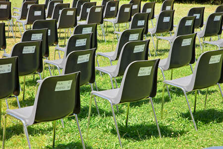 Open air cinema with black plastic seats spaced out due to coronavirus Sars-Cov-2 - Behind the seats is the seat number and the row to be respected - FILA means RAW - POSTO means PLACEの写真素材