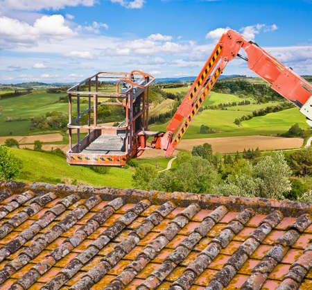 Aerial mechanical platform with protective basket to repair a roof safely in a construction siteの写真素材