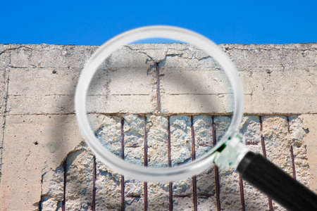 Old reinforced concrete structure with damaged and rusty metallic reinforcement that must be demolished - Concept seen through a magnifying glassの写真素材