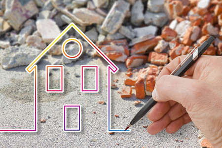 Hand drawing a colored house against a concrete and brick rubble debris - earthquake reconstruction concept imageの写真素材