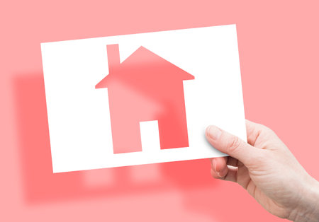 Construction of residential building - concept with hand holding a small houseの写真素材