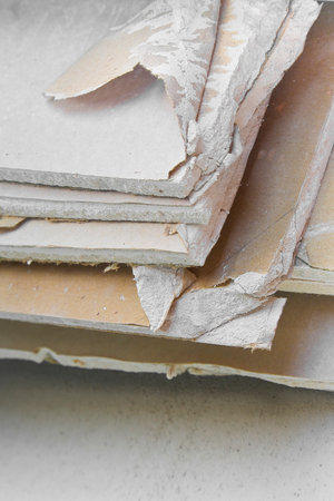Demolished plasterboard wall, made of plaster and cardboard, with fragments of material and dust in a construction siteの写真素材