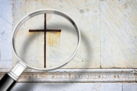 Looking for faith - concept image with a magnifying glass in front of a Christian crossの写真素材