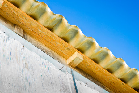 Old aged and damaged dangerous roof made of prefabricated and wave-shaped panels with wooden...