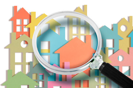 Real estate agent looks at the houses through a magnifying glass - Searching new home concept with colorful housesの写真素材