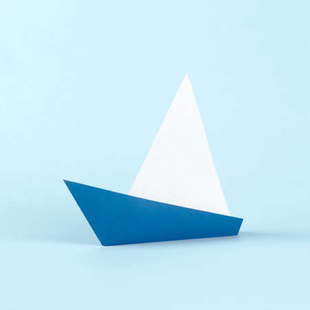 Origami white and blue paper sail boat on blue backgroundの写真素材