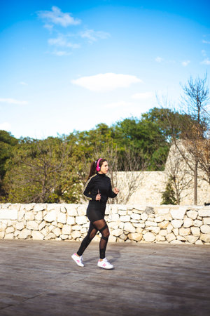 Female athlete running listening music with her headphones on her smartphone.の写真素材