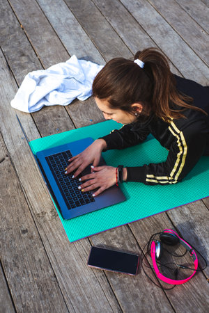 Fitness lifestyle. Girl is watching at a laptop video fitness lesson. Top viewの写真素材