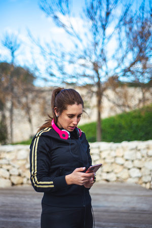 Portrait of a sporty young woman with headphones while exercising outdoors.の写真素材