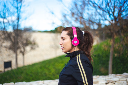 Portrait of a sporty young woman with headphones while exercising outdoors.の写真素材