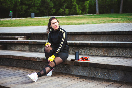 Portrait of a sporty young woman sit on wood stairs with sport accessories.の写真素材