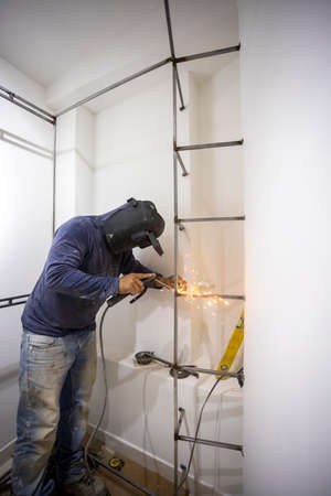 Worker welding a dressing room in a home renovation