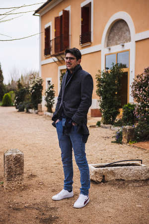 Young man standing waiting in front of his houseの写真素材