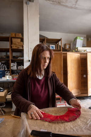 Vertical shot of a Spanish woman working at a hand fan design workshopの写真素材