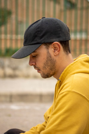 Portrait of a young male wearing a yellow hoodie and black cap in a streetの写真素材