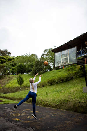 Vertical shot of a Hispanic woman with blonde hair playing basketball..の写真素材