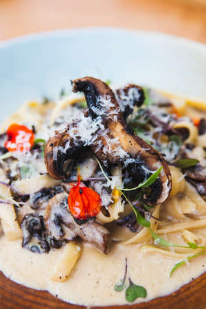 Vertical shot of delicious cream pasta with mushrooms, olives, and grated cheeseの写真素材