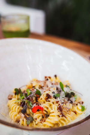 Vertical shot of delicious pasta carbonara with mushrooms and leaves in a ceramic bowlの写真素材