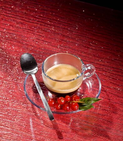 photo of espresso coffee with currants on red glasstableの写真素材