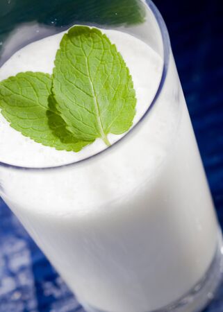 photo of hot milk in glass with two leaves of green fresh mintの写真素材