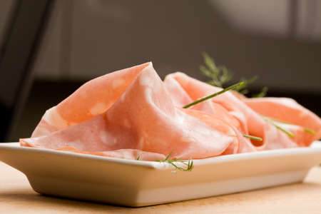 photo of thin slices of italian mortadella called also bologna on small rectangular plate served as appetizerの写真素材