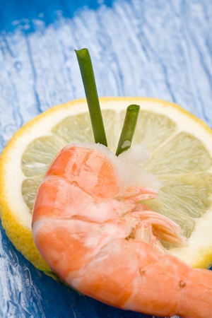 photo of delicious raw prawns with lemon slices and onions on white plateの写真素材