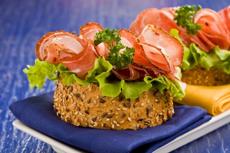 Delicious bacon and salad sandwich on blue cloth with parsleyの写真素材