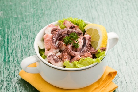 photo of delicious octopus salad appetizer on green glass table with yellow clothの写真素材