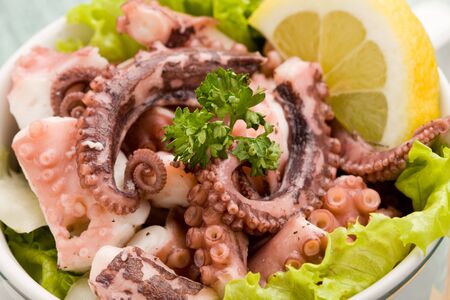 photo of delicious octopus salad appetizer on green glass table with yellow clothの写真素材