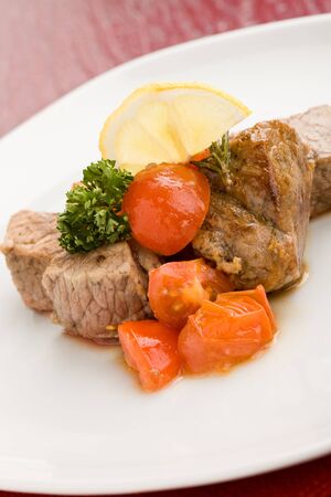 photo of delicious meat with fresh tomatoes lemon and parsleyの写真素材
