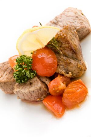 photo of delicious meat with fresh tomatoes lemon and parsleyの写真素材