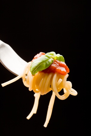 photo of fork with wrapped spaghetti with tomatoe Sauce and basilの写真素材