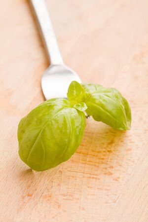 photo of fork with basil leaves on wooden tableの写真素材
