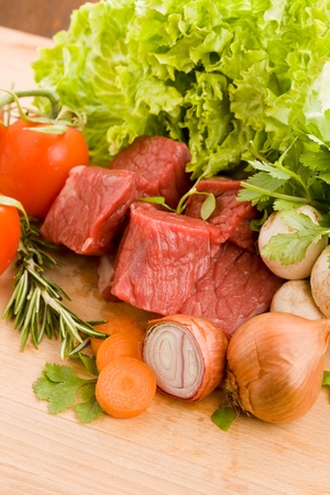 photo of diced raw meat with vegetables on a wooden chopping boardの写真素材