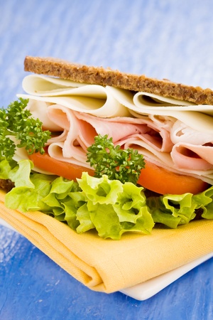 photo of delicious big cheese and ham sandwich with lettuce on blue glass tableの写真素材