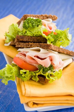 photo of delicious big cheese and ham sandwich with lettuce on blue glass tableの写真素材