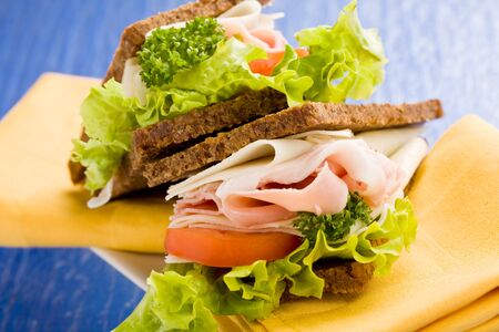 photo of delicious big cheese and ham sandwich with lettuce on blue glass tableの写真素材
