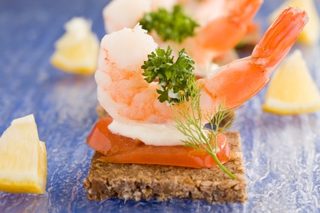 photo of delicious starter made of prawns and tomatoes on black breadの写真素材