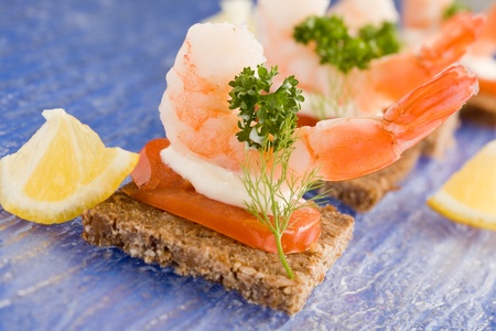 photo of delicious starter made of prawns and tomatoes on black breadの写真素材