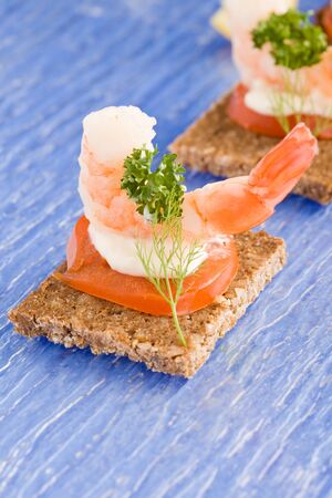 photo of delicious starter made of prawns and tomatoes on black breadの写真素材