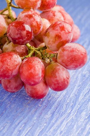 photo of delicious red grape on blue glass tableの写真素材