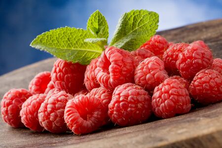 photo of delicious red raspberries with mint leaves on wooden tableの写真素材