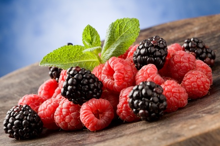 photo of delicious berries with meant leaves on wooden table の写真素材